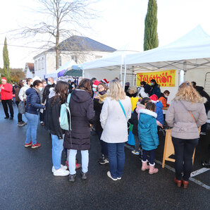 Vue générale du stand du Conseil Communal Enfants et Jeunes avec beaucoup de personnes devant. A gauche de la photo trois personnes animent la journée en jouant des airs de musiques avec leurs instruments