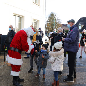 Père Noël distribuant des bonbons à des enfants sur le parvis de la mairie