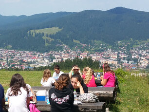 Photo en prise en altitude surplombant la ville de Bivolarie avec des adolescents pique-niquant en premier plan